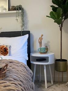 a bed with a night stand next to a potted plant at Charming Family Home with Gym in Henley on Thames