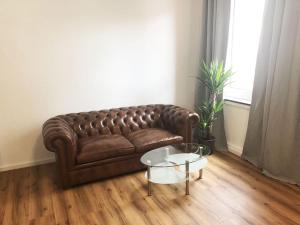 a brown leather couch in a living room with a table at Apartment in Innenstadt Bielefeld in Bielefeld