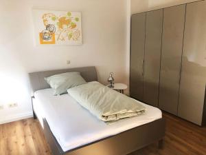 Schlafzimmer mit einem Bett mit weißer Bettwäsche und einem Schrank in der Unterkunft Apartment in Innenstadt Bielefeld in Bielefeld