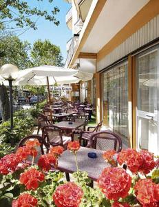 un patio extérieur avec des tables, des chaises et des fleurs dans l'établissement Hotel Giulio Cesare, à Cattolica