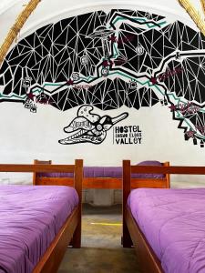 2 camas en una habitación con un mural en la pared en Hostal Cosmo Elqui, en Rivadavia