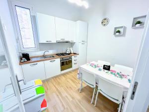 uma cozinha com armários brancos e uma mesa e cadeiras em Kenzia Apartment em Trapani