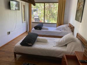 3 camas en una habitación con ventana en El Pillan "Travelers" House, en Santiago