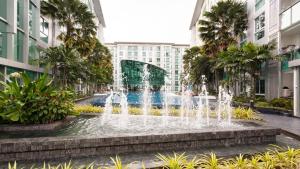 a fountain in front of a building with palm trees at Pattaya City Center Residence K in Pattaya Central
