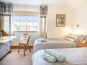 a bedroom with two beds and a desk and a chair at 3 Bed in Southerndown 57715 in Southerndown