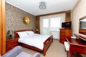 Un dormitorio con una cama, un escritorio y un televisor. en Alga Baltic Resort, en Świnoujście