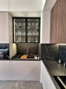 Una cocina con gabinetes blancos y un fregadero con vasos. en Crown Apartments - BW Sole, en Belgrado