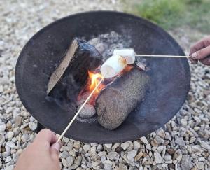 een persoon kookt eten boven een kampvuur bij Peggy’s Hut in Astbury