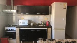 a kitchen with black cabinets and a white refrigerator at Zapala departamentos por día in Zapala