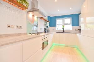 a kitchen with white cabinets and blue walls at Princes Esplanade in Cowes