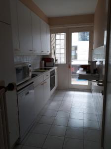 eine Küche mit weißen Schränken und einem großen Fenster in der Unterkunft Appartement 2 chambres spacieux pour 4 personnes in Knokke-Heist