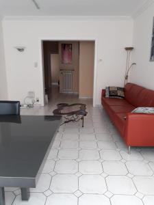 ein Wohnzimmer mit einem roten Sofa und einem Tisch in der Unterkunft Appartement 2 chambres spacieux pour 4 personnes in Knokke-Heist