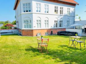 a yard with chairs and tables in front of a house at aday - City Central Mansion - 4 bedroom apartment in Aalborg