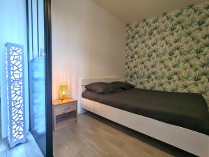 Habitación pequeña con cama y mesita de noche en Bel Appartement Meximieux Centre Ville 2 chambres, en Meximieux