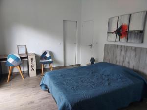 a bedroom with a blue bed and two chairs at LE PETIT PARADIS in Sainte-Rose