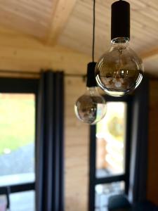 two glass lights hanging from a ceiling with a window at Górna Kudowa Domki Wypoczynkowe in Kudowa-Zdrój