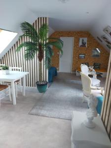 a living room with a palm tree and a table and chairs at Les Suites de Véronique, chez Véronique Olive in Saint-Pair-sur-Mer