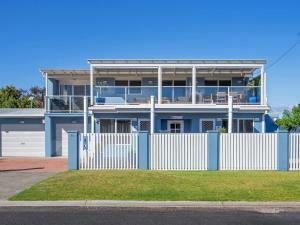 a blue house with a white fence in front of it at Kalisti Suites - Fira Suite in Port Sorell