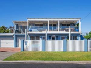 une maison bleue avec une clôture blanche devant elle dans l'établissement Kalisti Suites - Fira Suite, à Port Sorell