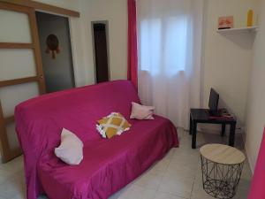 a purple couch with pillows on it in a room at Abrivado Appartements meublés dans une grande propriété en rez de jardin in Aimargues