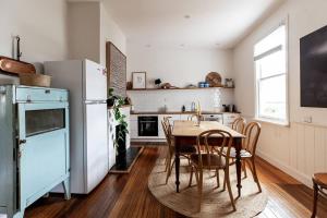 uma cozinha com uma mesa e cadeiras e um frigorífico em Galvin Town Cottage, convenient to CBD em Kings Park