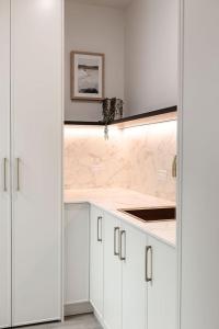a kitchen with white cabinets and a marble counter top at Large Apartment in Launceston- Timeless Luxury in Launceston