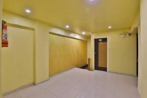 a hallway with yellow walls and a door and a room at SPOT ON Hotel Shreeji Palace in Ahmedabad