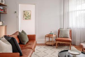 uma sala de estar com um sofá e uma cadeira em Mulgrave Street Cottage- renovated comfort em Kings Park