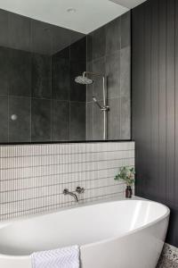 uma casa de banho com uma banheira branca e azulejos pretos em Mulgrave Street Cottage- renovated comfort em Kings Park