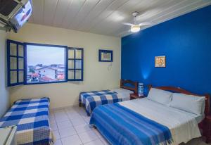 - une chambre avec 2 lits et un mur bleu dans l'établissement Pousada Canto da Vila, à Saquarema