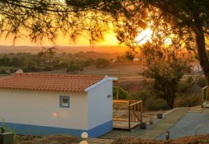 un petit bâtiment blanc avec un coucher de soleil en arrière-plan dans l'établissement Monte Sardinha, à Santiago do Cacém