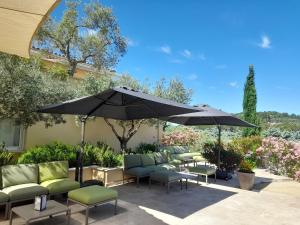 eine Terrasse mit Tischen, Stühlen und einem Sonnenschirm in der Unterkunft Le Clos Saint Michel Resort & Spa in Malaucène