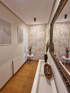 einen Flur mit Treppe mit Spiegel und Blumen an der Wand in der Unterkunft a 2 min de Gascona in Oviedo