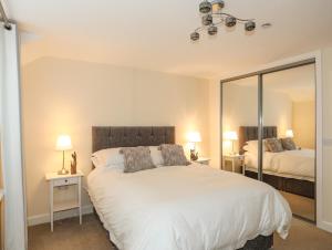 a bedroom with a large white bed and a mirror at Arnant in Pwllheli