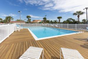 a swimming pool on a wooden deck with two chairs at Palmetto 306 in Orange Beach