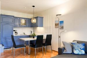 cocina con armarios azules, mesa y sillas en Hanse-Hof Wohnung 05, en Boltenhagen