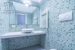 Baño de azulejos azules con lavabo y espejo en Vittoria Apartments: Cantarane 1, en Vicenza