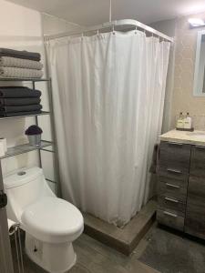 y baño con cortina de ducha blanca y aseo. en ¡Cómodo departamento con la mejor ubicación!, en Tijuana