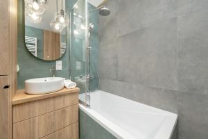 a bathroom with a sink and a tub and a mirror at Exclusive River View Apartment with Balcony & FREE GARAGE by Renters Prestige in Wrocław