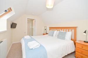 a bedroom with a large white bed and a television at 24 Tollgate Cottages in Seaview