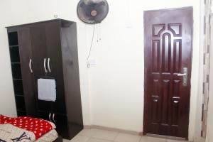um quarto com uma porta castanha e uma ventoinha em Smilley's Place Ms-Tammy em Lagos
