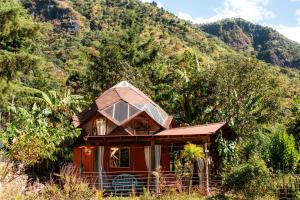 a small red house in the middle of a mountain at Casa Curativa in Tzununá