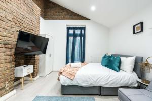 a bedroom with a bed and a tv and a brick wall at Central-comfyStudio-quite in London