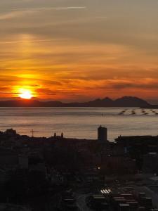 una puesta de sol sobre un cuerpo de agua con una ciudad en VistasAragon, en Vigo