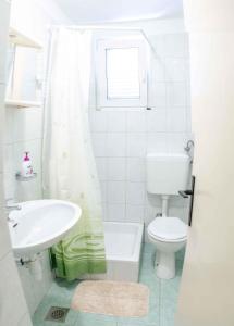 ein weißes Bad mit einem WC und einem Waschbecken in der Unterkunft Apartments in Lopar - Insel Rab 26467 in Lopar