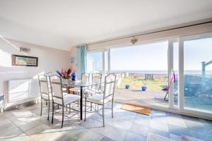 een eetkamer met een tafel en stoelen en uitzicht op de oceaan bij Family Haven by the Waves Direct Beach Access in Pevensey