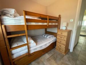 two bunk beds in a room with a dresser at Family Haven by the Waves Direct Beach Access in Pevensey