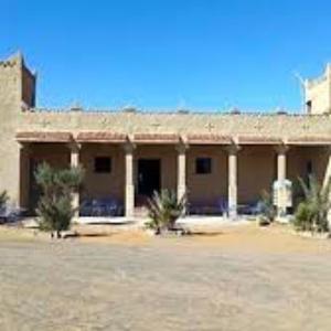 un grande edificio con alberi di fronte di Hostel la palmeraie merzouga a Merzouga