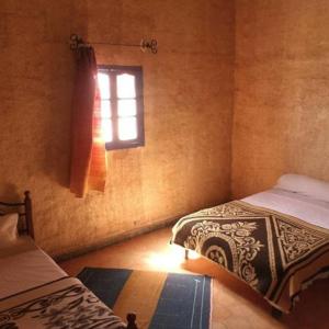 a bedroom with two beds and a window at Hostel la palmeraie merzouga in Merzouga