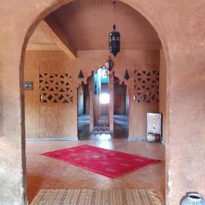 um quarto grande com um tapete vermelho no chão em Hostel la palmeraie merzouga em Merzouga